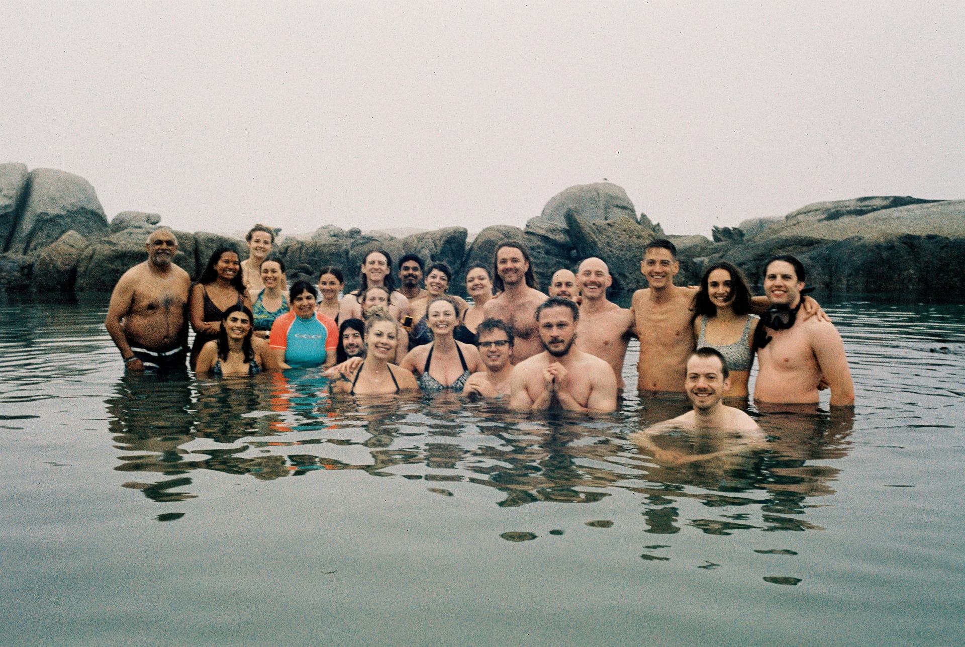Beach Bobbers gathered together in the ocean beside coastal rocks.